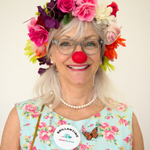 Femme clown nez rouge, couronne fleurs colorées.
