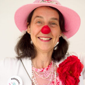 Femme avec nez rouge de clown et chapeau rose.