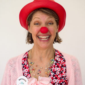 Femme souriante avec chapeau rouge et nez de clown.
