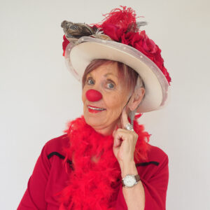 Clown senior en costume rouge avec nez rouge.