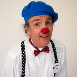 Homme déguisé en clown avec nez rouge.